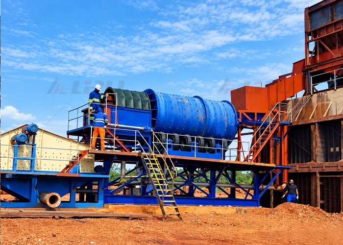 Rotary scrubber installed at an ore processing plant, with workers inspecting the drum and connected screening equipment.