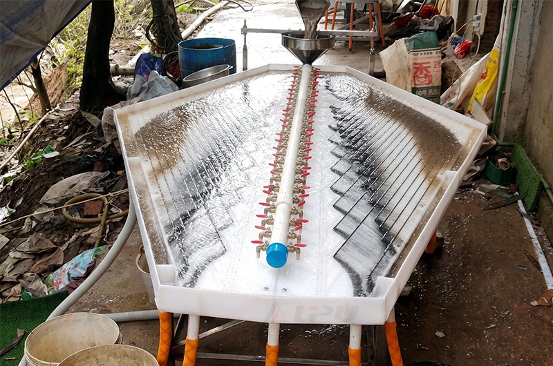 Gemini gold shaking table in operation showing wash water distribution and distinct black heavy mineral separation bands.