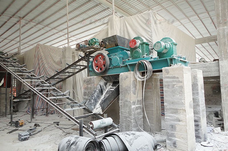 Double roll crusher processing limestone at an indoor material processing site