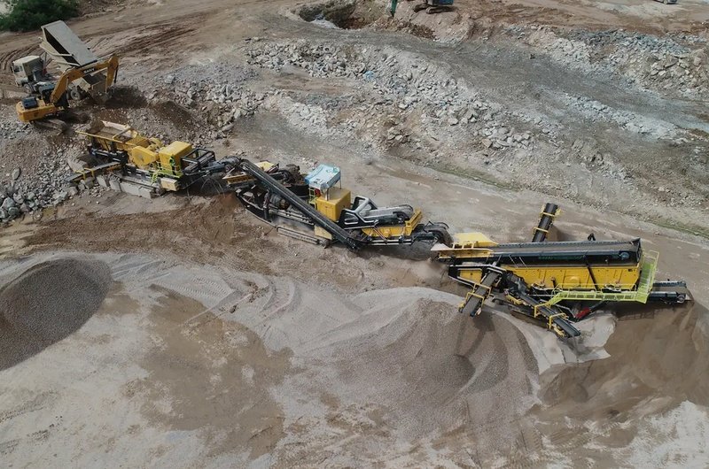 Mobile crushing and screening plant operating at a quarry site with crushers conveyors and aggregate stockpiles