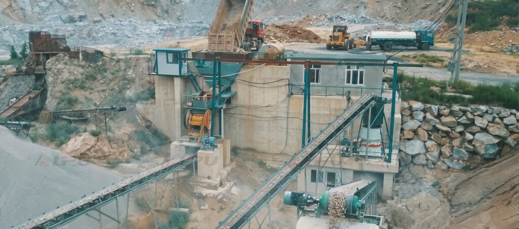 Hard rock crushing plant with ore receiving structures, belt conveyors, and material transfer equipment.