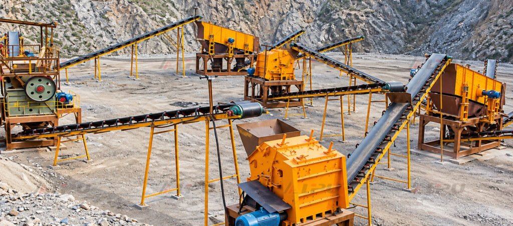 Real hard rock ore crushing plant with primary and secondary crushers, screening equipment, and belt conveyors at a mineral processing site.
